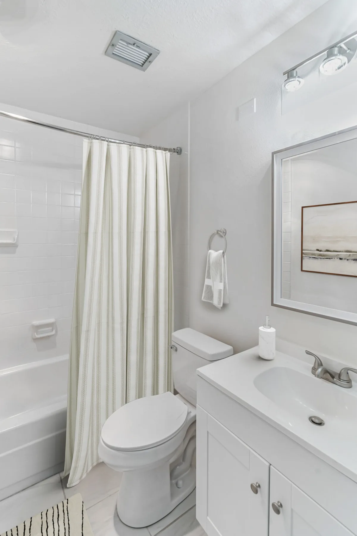 Bathroom with tub shower and white vanity at ABQ Encore Apartments