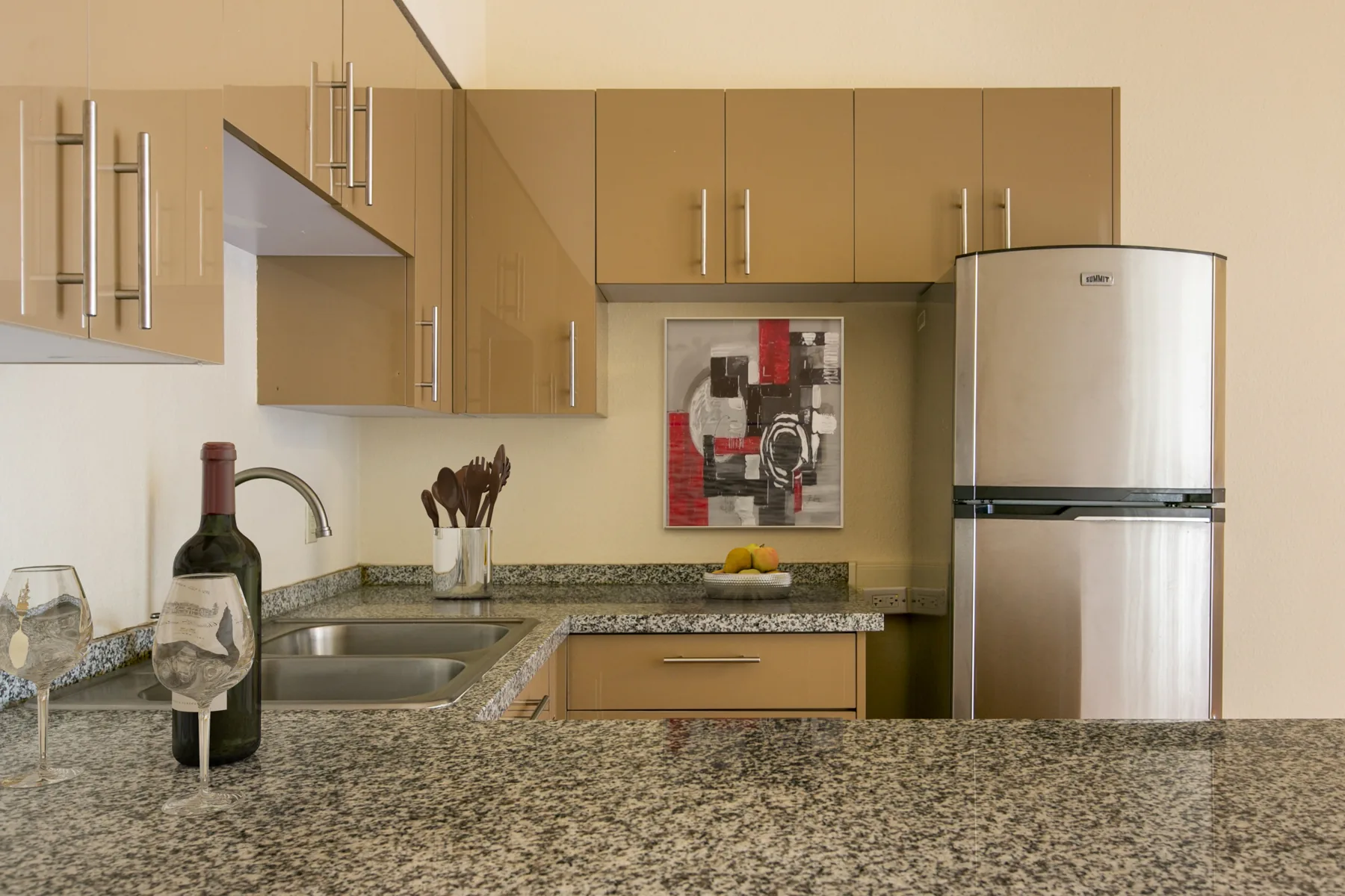 Kitchen with granite counters, tan cabinets and stainless refrigerator at ABQ Encore Apartments